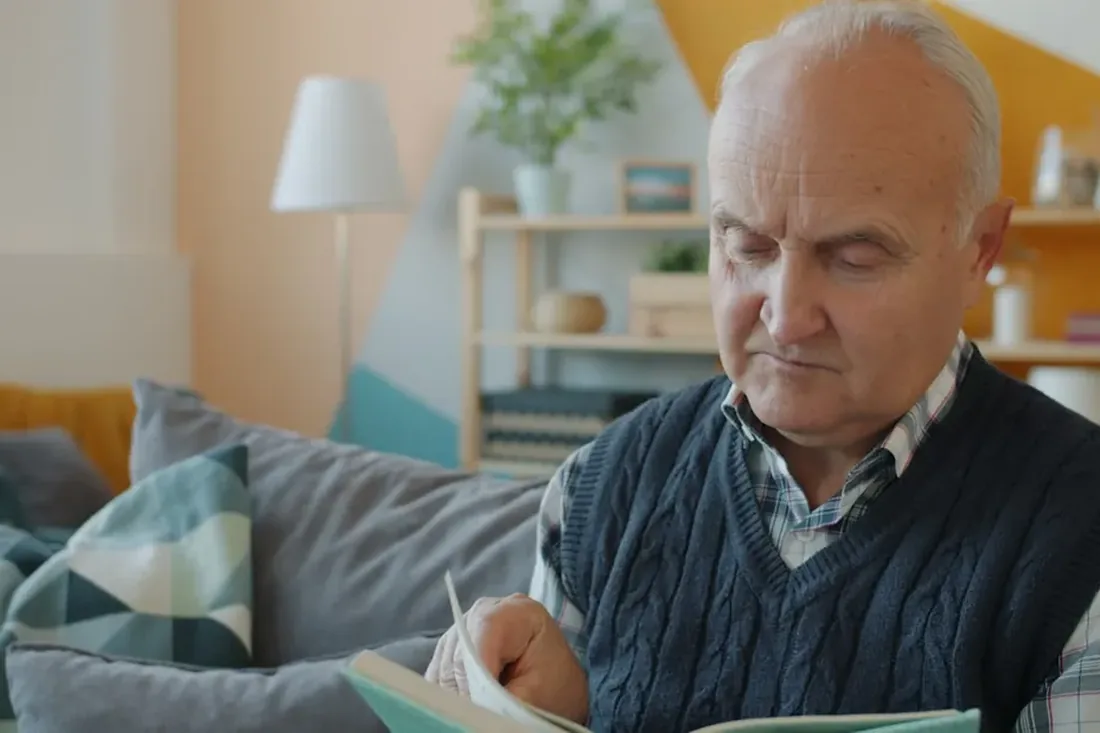 Imagem ilustrativa: senhor idoso lendo sentado na sala de casa